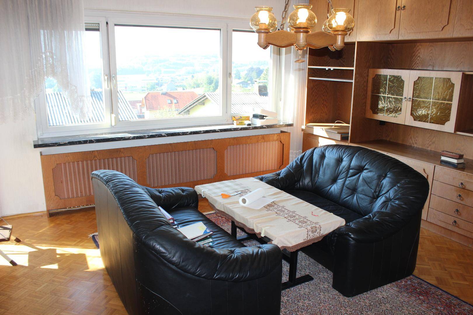 Wohnzimmer mit schwarzen Ledersofas, einem kleinen Tisch und einem großen Fenster mit Ausblick.