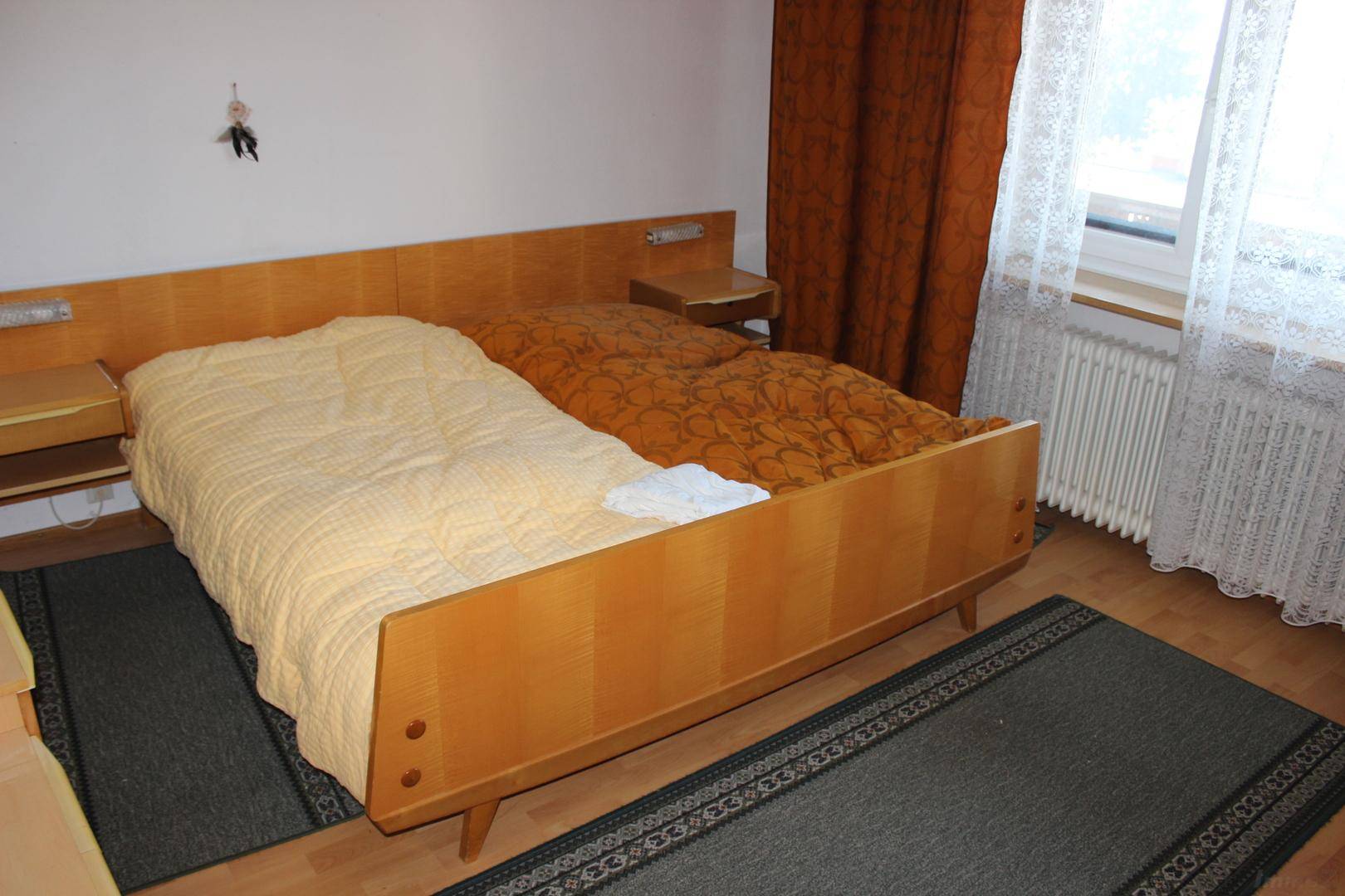 Schlafzimmer mit zwei Einzelbetten in einem Holzrahmen und Holzboden, hell und funktional.