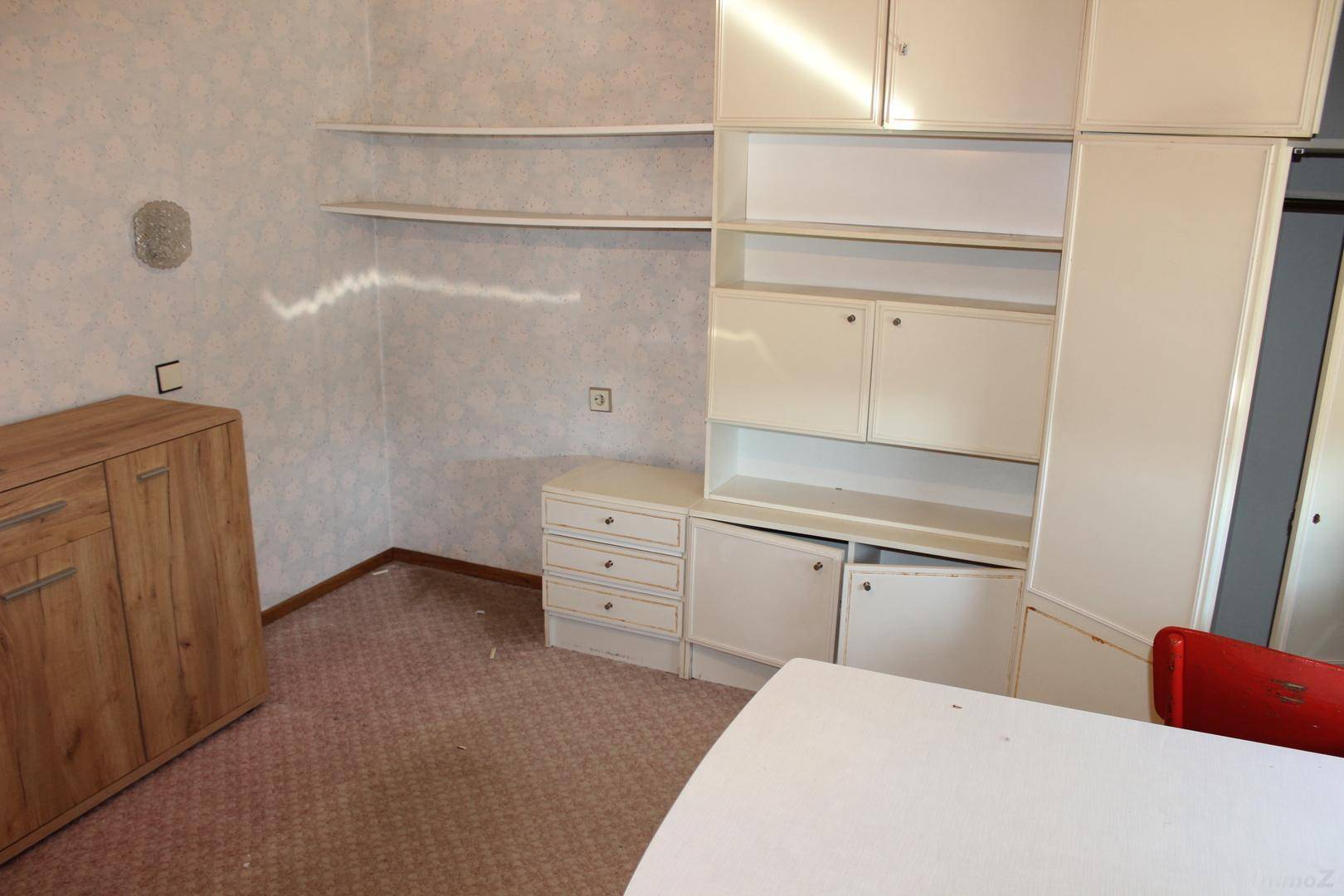 Raum mit weißen Einbauschränken und Regalen sowie einem Teppichboden, viel Stauraum bietend.