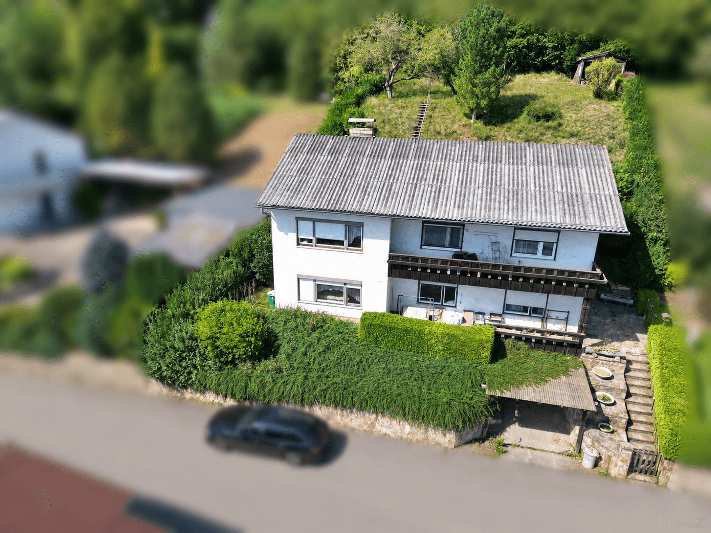 Luftaufnahme eines Hauses mit Garten und umliegender grüner Landschaft in einer ländlichen Gegend.