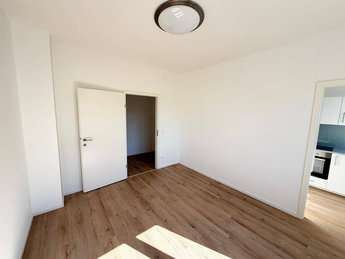 Helles Zimmer mit Laminatboden und direktem Zugang zur modernen Küche.