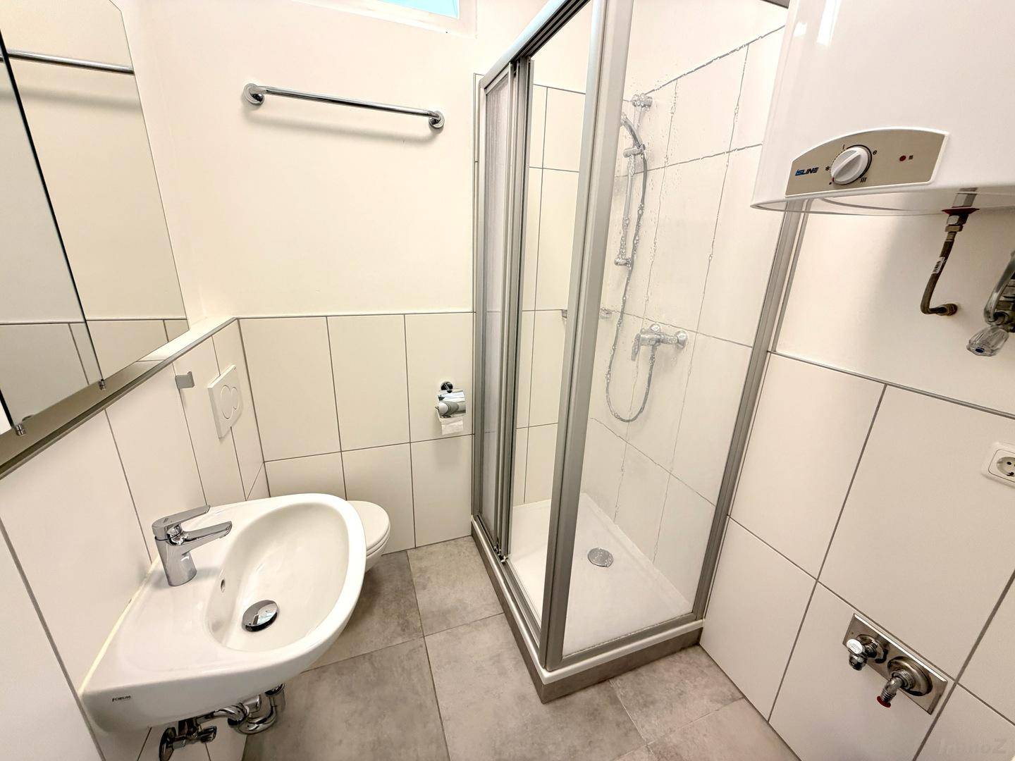 Modernes Badezimmer mit Duschkabine, Waschbecken, WC und Spiegelschrank.