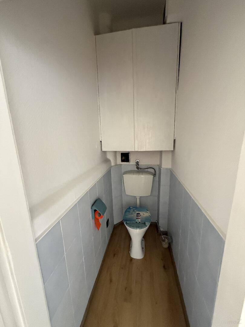 Kleines Gäste-WC mit WC, blauen Fliesen und einem Hängeschrank für zusätzlichen Stauraum.