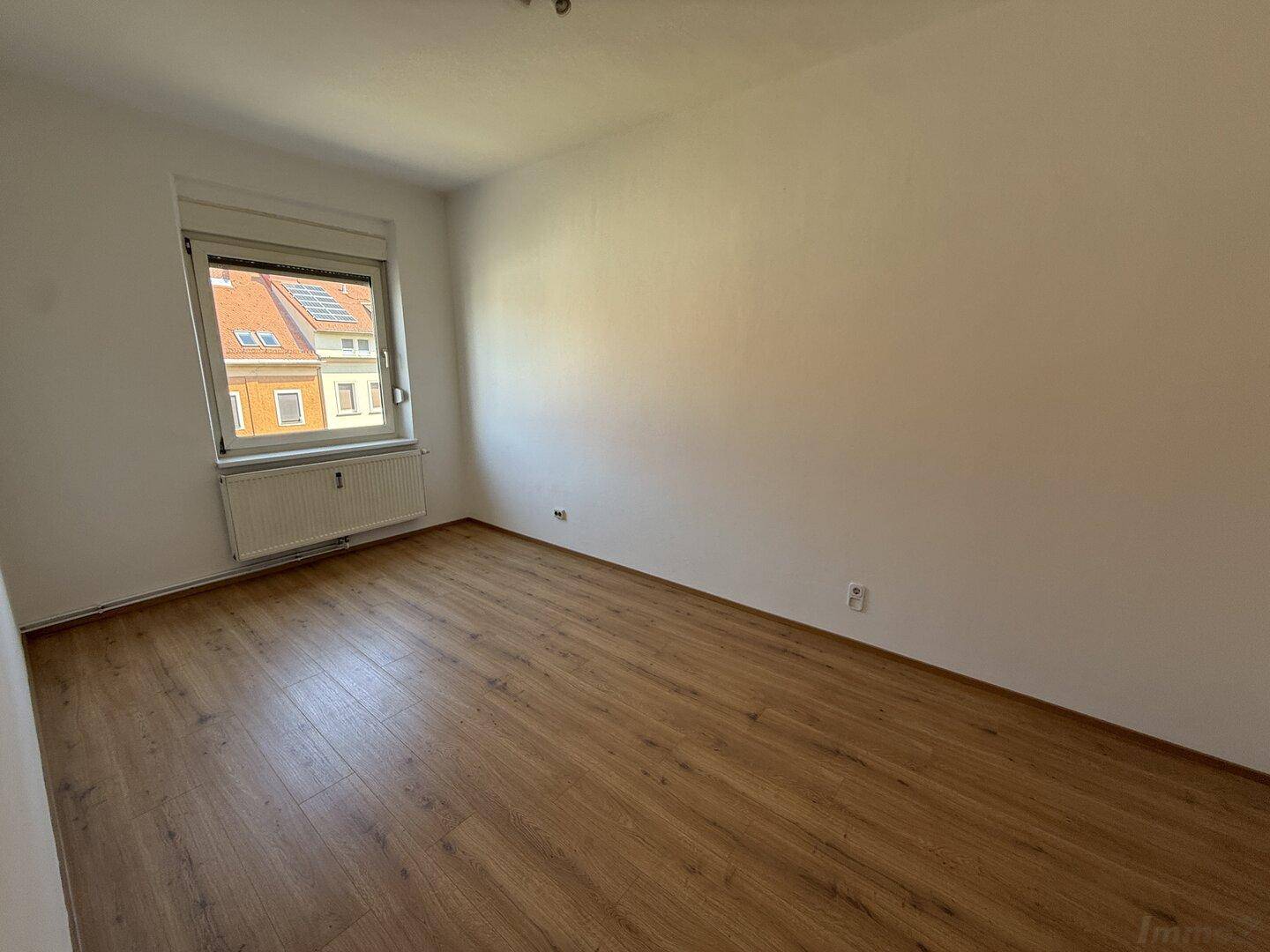 Geräumiges Zimmer mit Laminatboden und Fenster, das viel Tageslicht hereinlässt und eine angenehme Atmosphäre schafft.