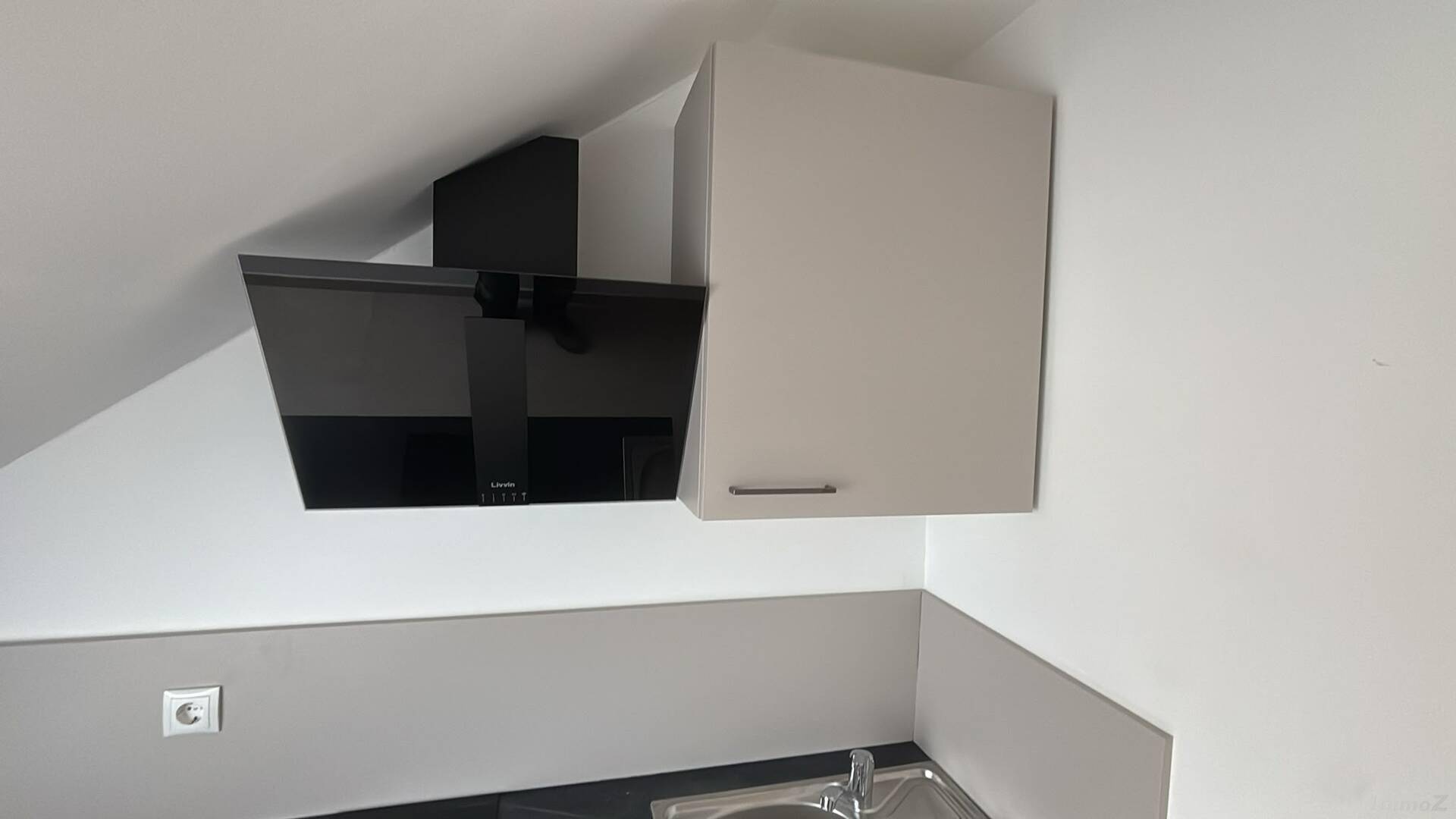 Moderner Dunstabzug und Hängeschrank in der Dachgeschossküche mit schrägen Wänden.