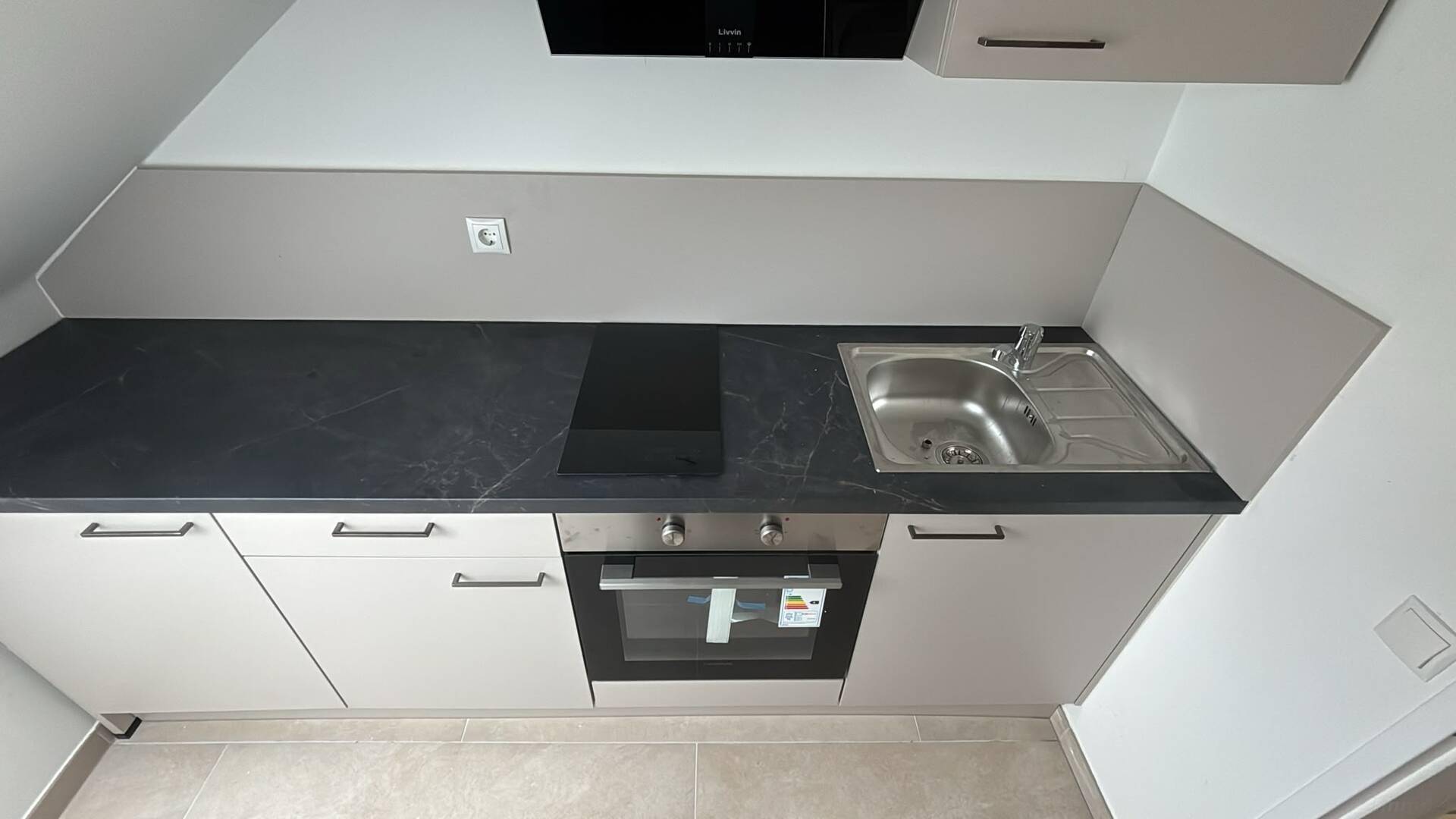 Funktionale Küchenzeile mit integriertem Backofen, Induktionskochfeld und Edelstahlspüle.