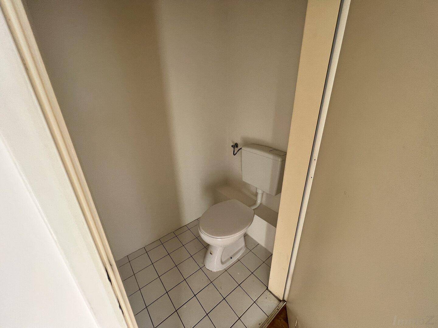 Kleines separates WC mit weißen Fliesen und einfacher Toilette, ideal für Gäste.