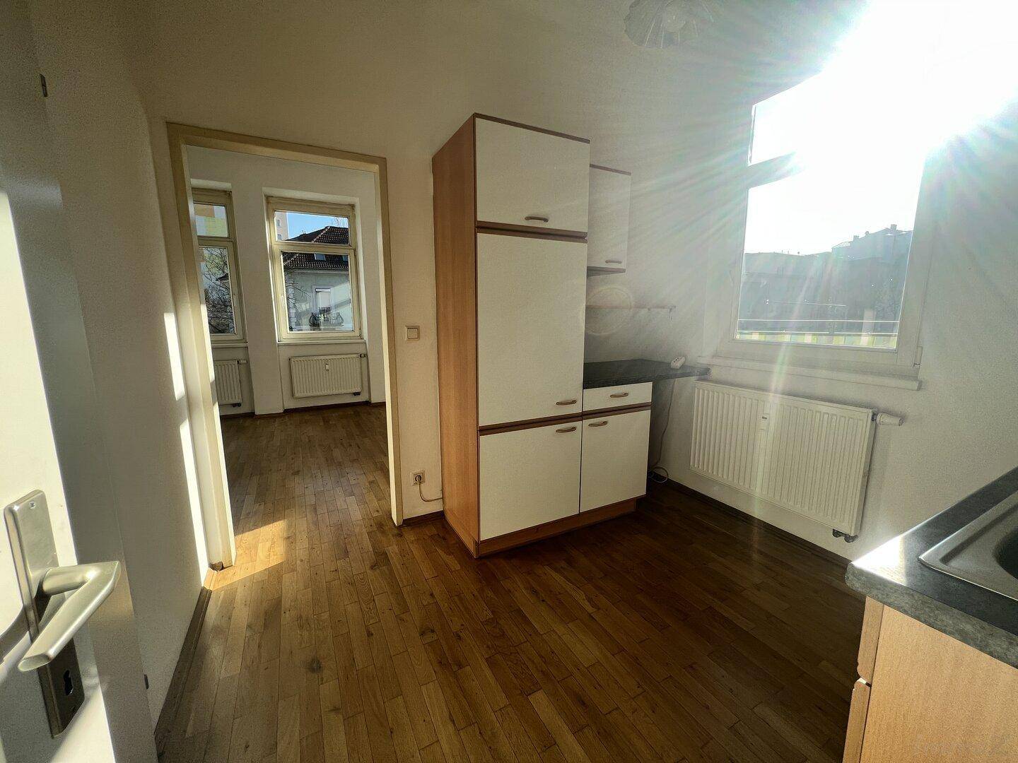 Helle Küche mit Holzboden und einfacher Einbauküche, die viel Sonnenlicht erhält.