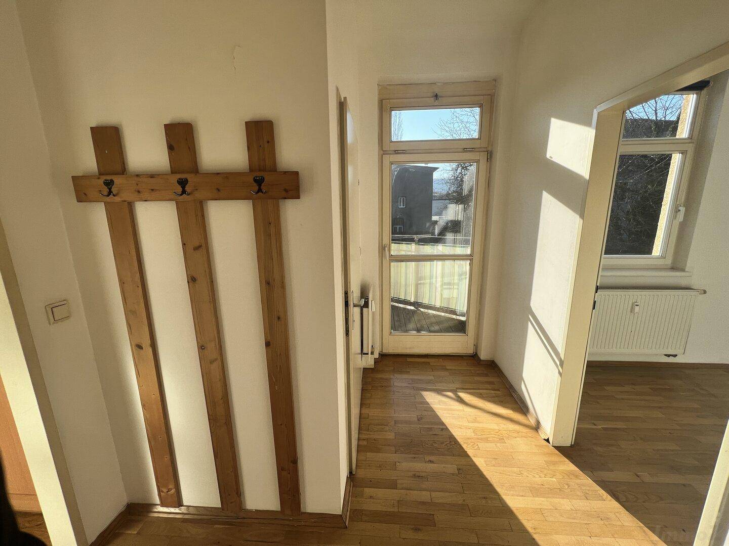 Heller Flur mit Holzboden und Garderobe, der zu weiteren Räumen führt.