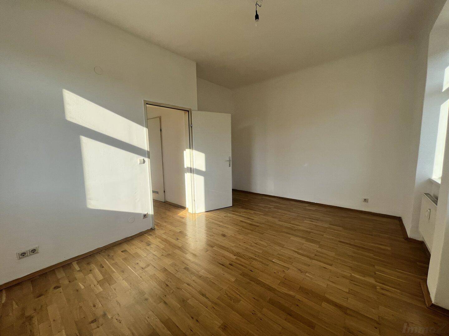 Großes, helles Wohnzimmer mit Holzboden und viel Platz für individuelle Gestaltung.
