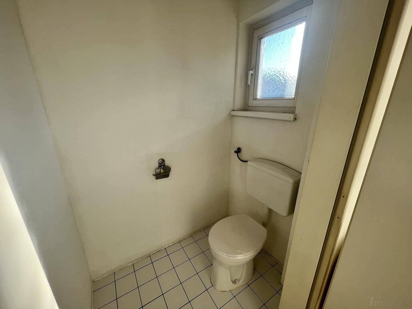 Separates WC mit Fenster und Fliesenboden, funktional und hell.