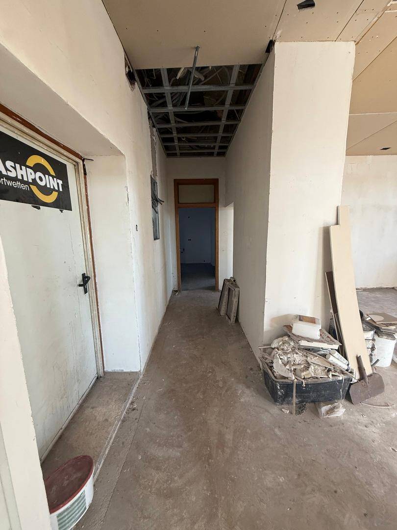 Flur im Rohbauzustand mit sichtbarer Deckenkonstruktion und Baumaterialien, die auf den Abschluss warten.