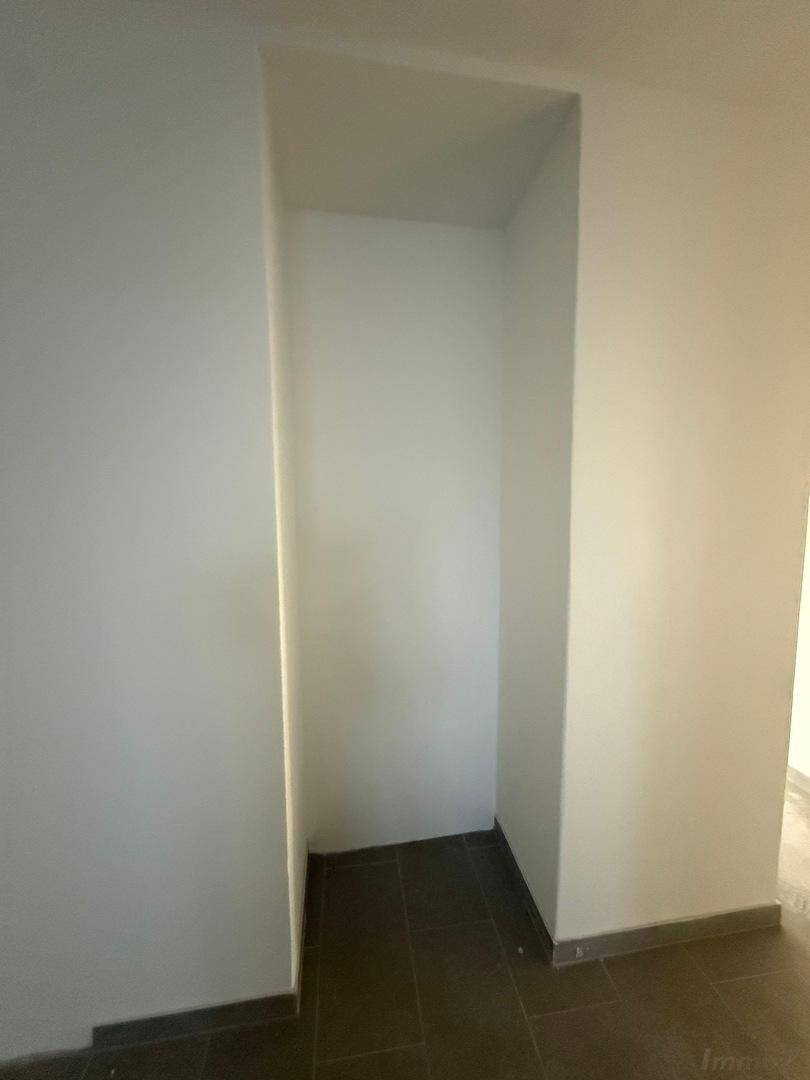 Heller Nischenbereich mit grauen Fliesen und weißen Wänden, ideal als Abstellraum oder Garderobe.