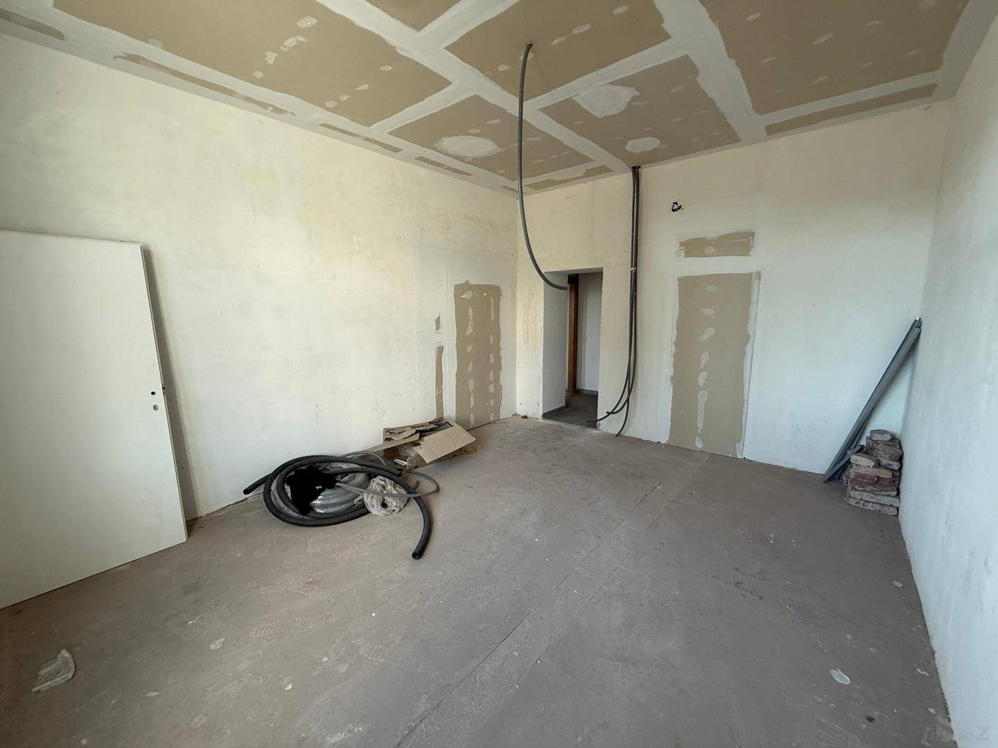 Rohbau-Raum mit Betonboden und unfertigen Wänden, der auf die Fertigstellung der Innenräume wartet.