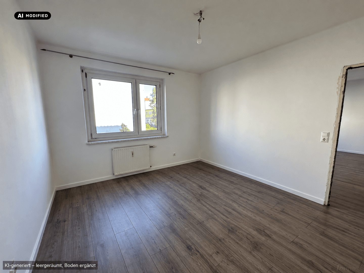 Heller, leerer Raum mit Fenster und Laminatboden, ideal für verschiedene Nutzungsmöglichkeiten.