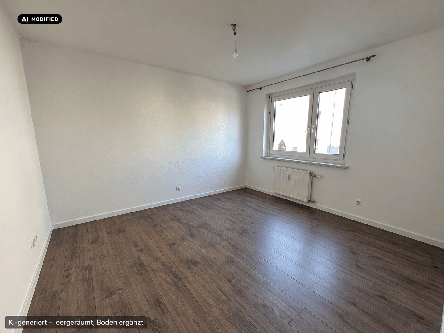 Geräumiger, leerer Raum mit Laminatboden und großem Fenster, das viel Tageslicht hereinlässt.