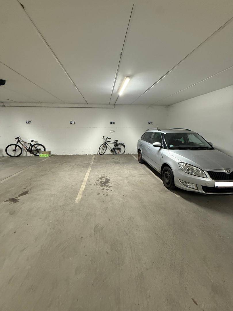 Heller Tiefgaragenstellplatz mit Betonboden, Platz für ein Auto und Fahrräder.
