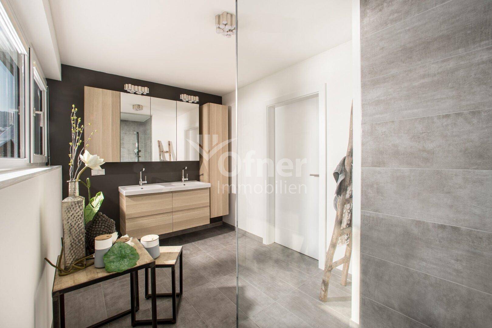Modernes Badezimmer mit Doppelwaschbecken, großem Spiegel und grauen Fliesen.