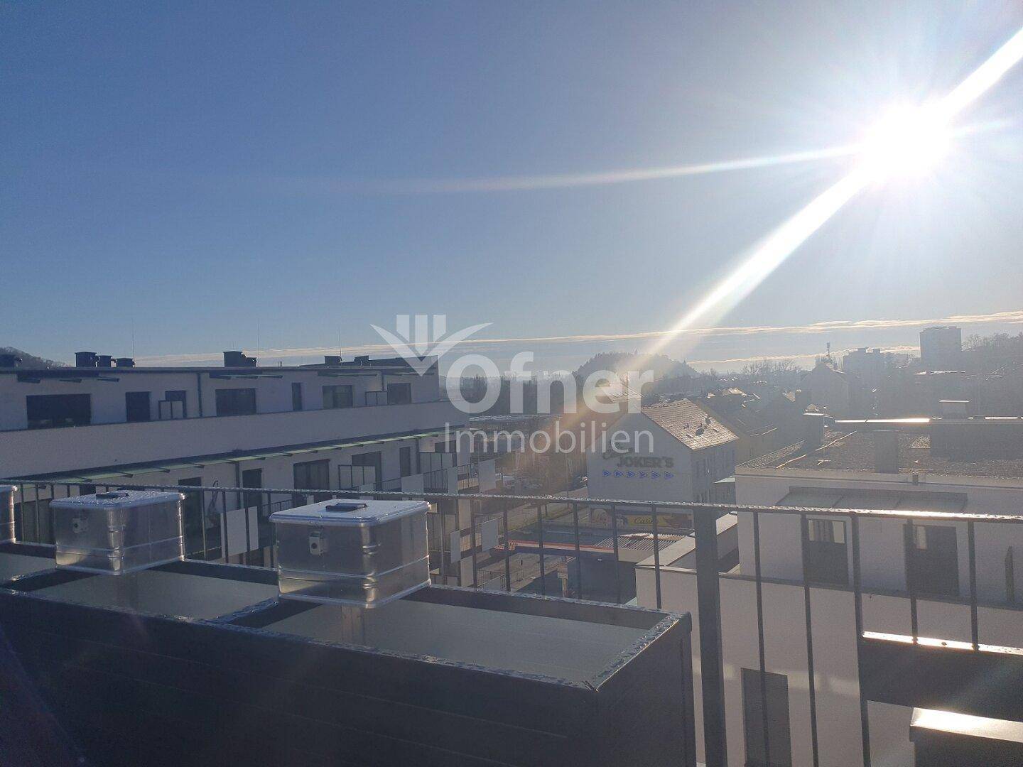 Sonnige Dachterrasse mit weitem Blick über die umliegenden Gebäude und die Stadt.