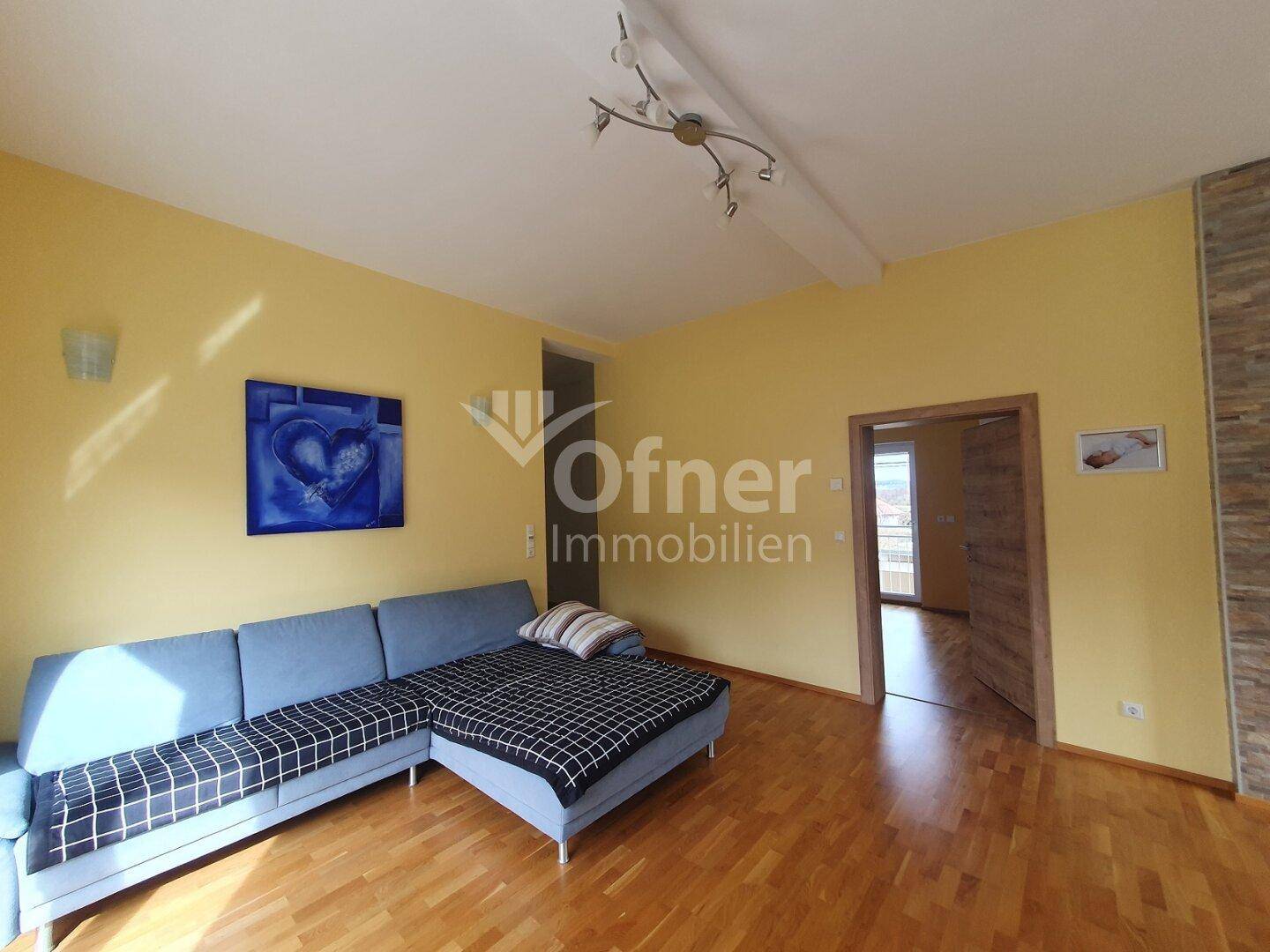 Gemütliches Wohnzimmer mit gelben Wänden, Holzboden und einem bequemen Ecksofa.