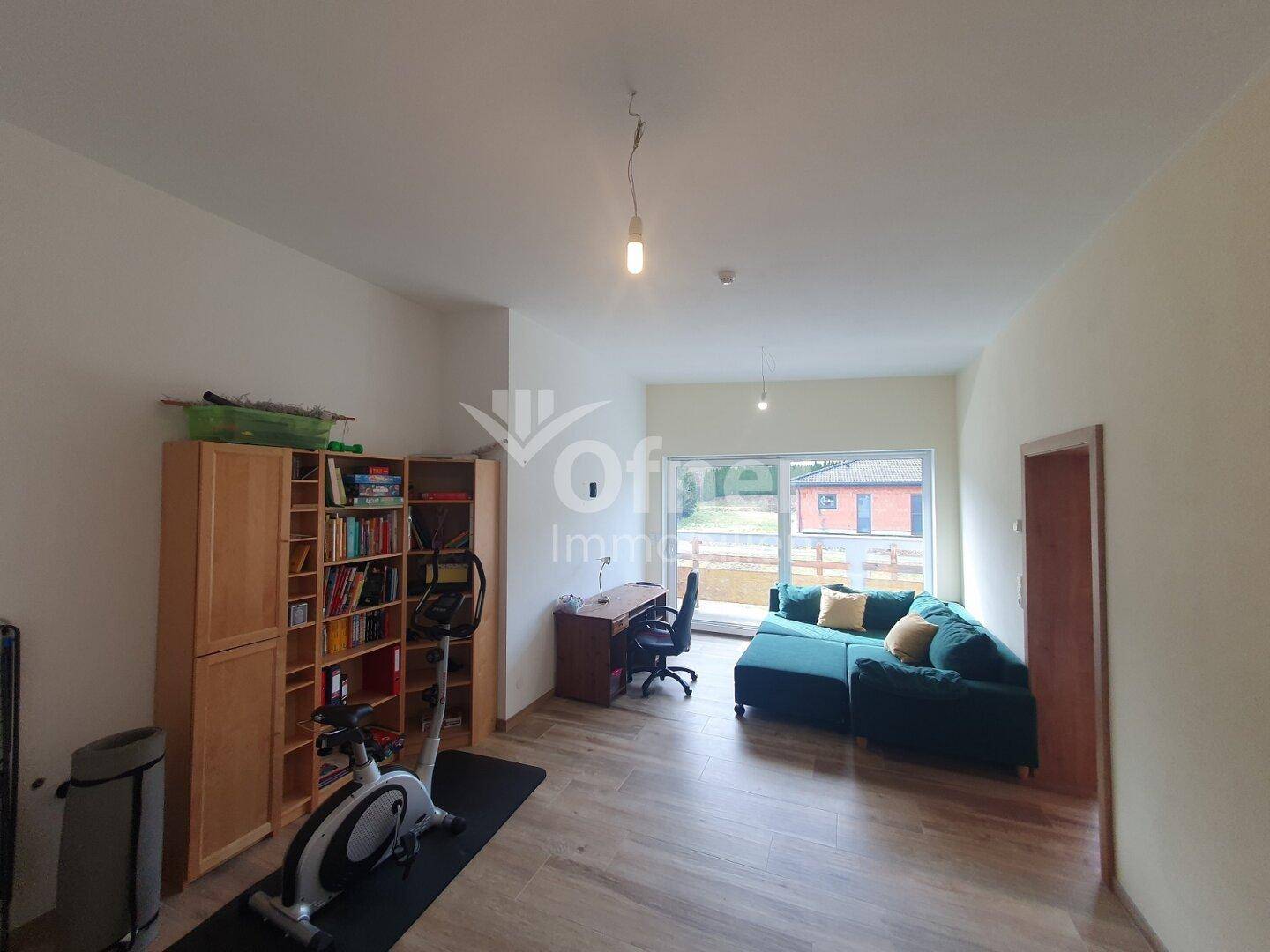 Vielseitiger Raum mit Bücherregal, Schreibtisch und Fitnessgeräten, ideal als Büro oder Hobbyraum.