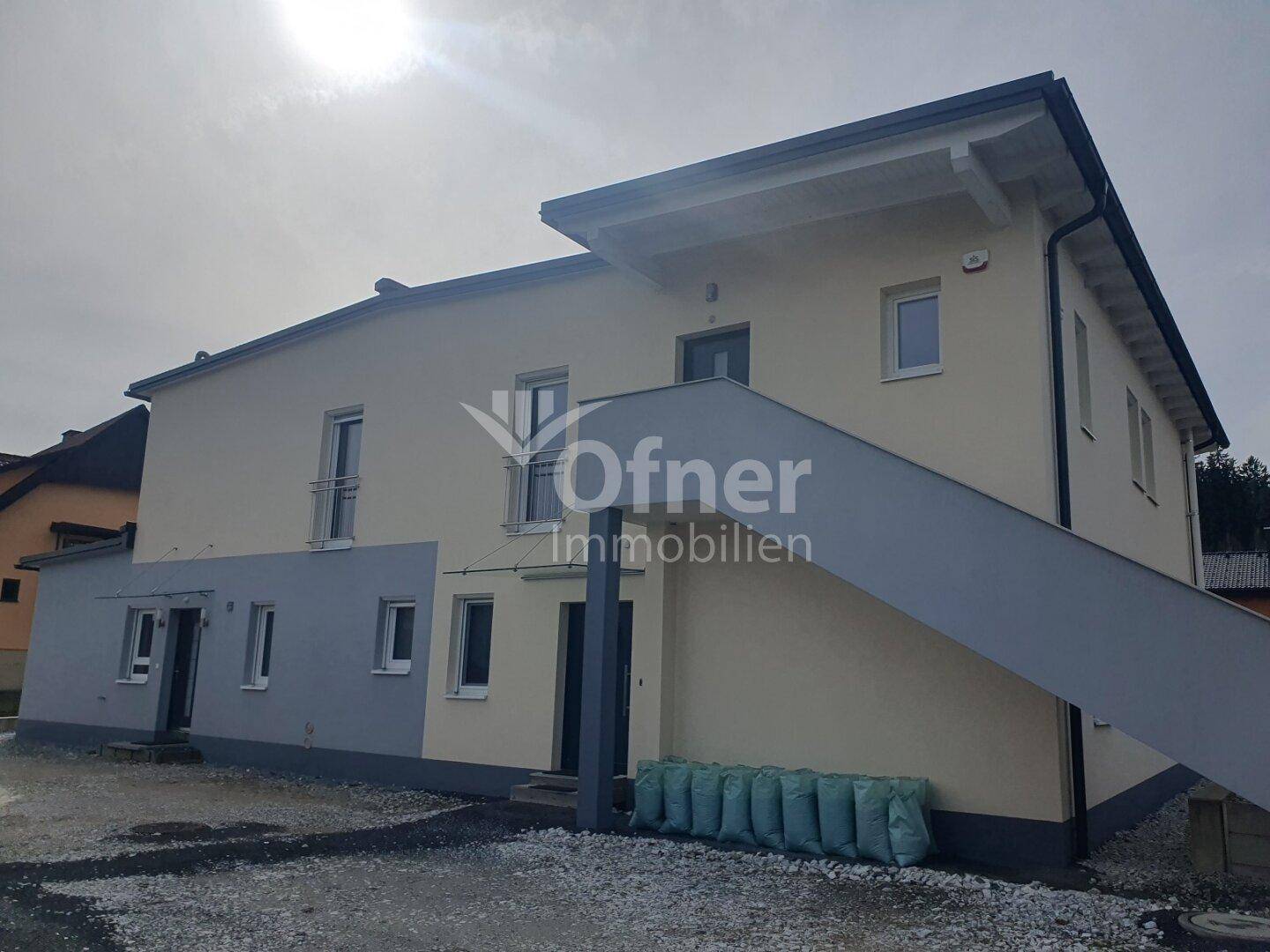 Seitenansicht des modernen Hauses mit heller Fassade und Außentreppe.