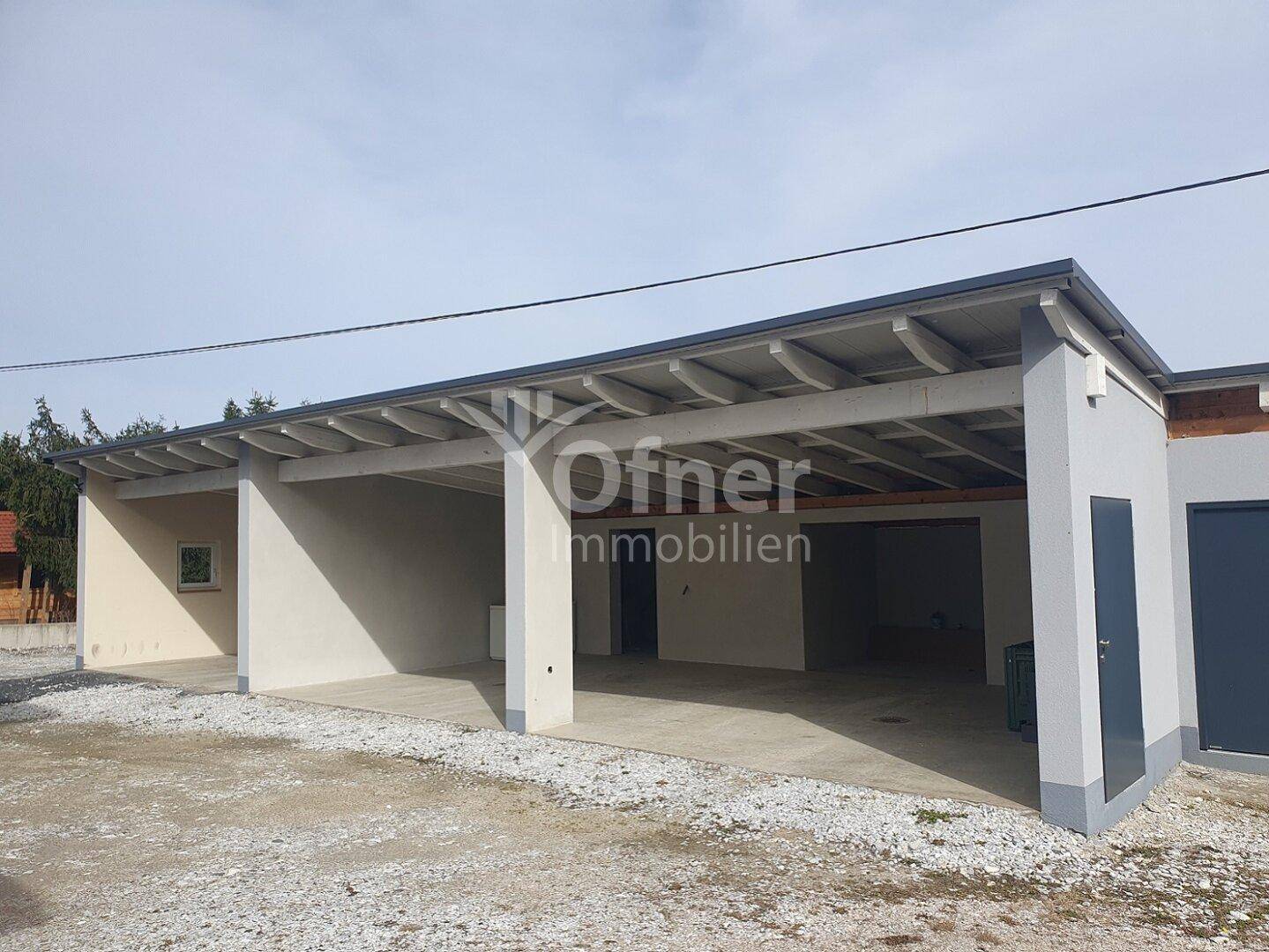 Geräumiger Carport mit mehreren Stellplätzen und angrenzendem Abstellraum.