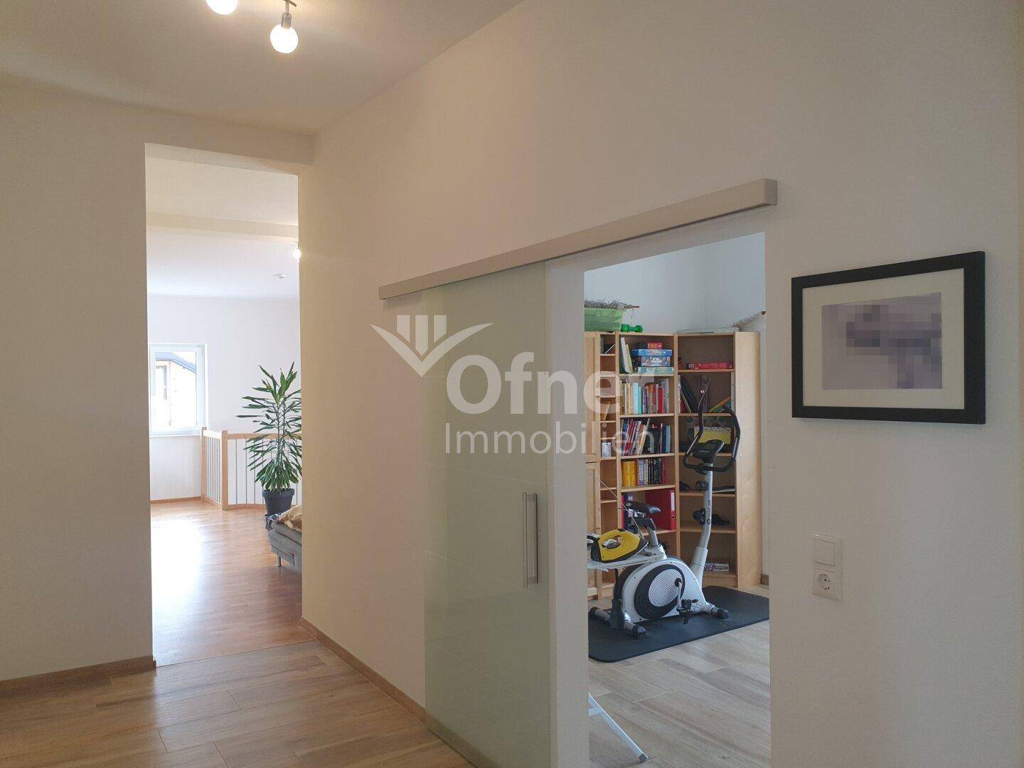 Heller Flur mit Glasschiebetür, die zu einem weiteren Zimmer führt.