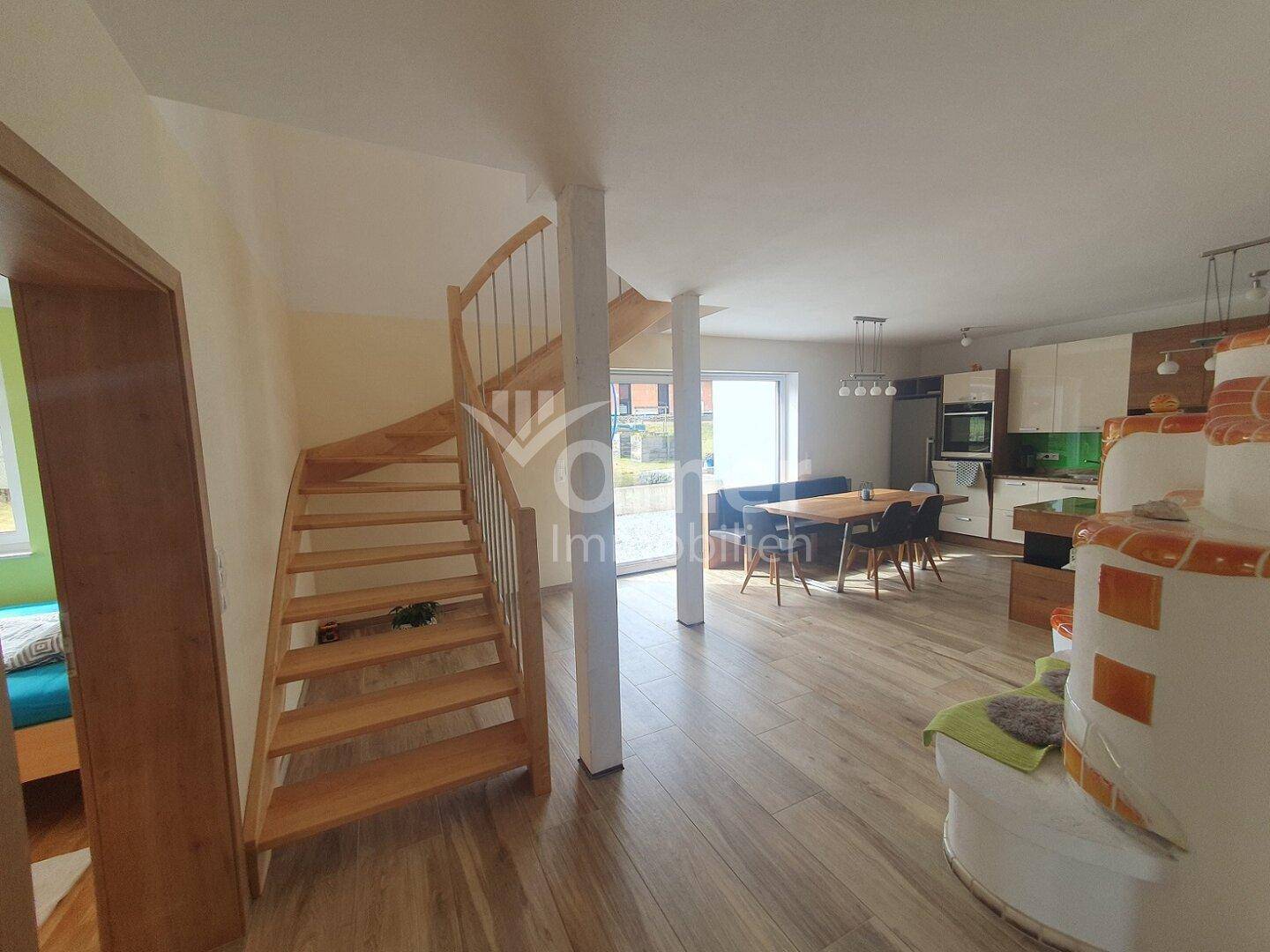 Heller Eingangsbereich mit Holztreppe, die zum offenen Wohn- und Essbereich führt.