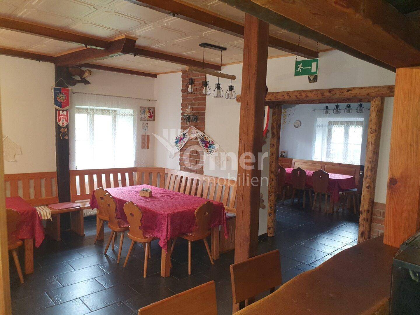 Rustikaler Essbereich mit Holzbalken, dunklem Fliesenboden und traditionellen Sitzgelegenheiten.