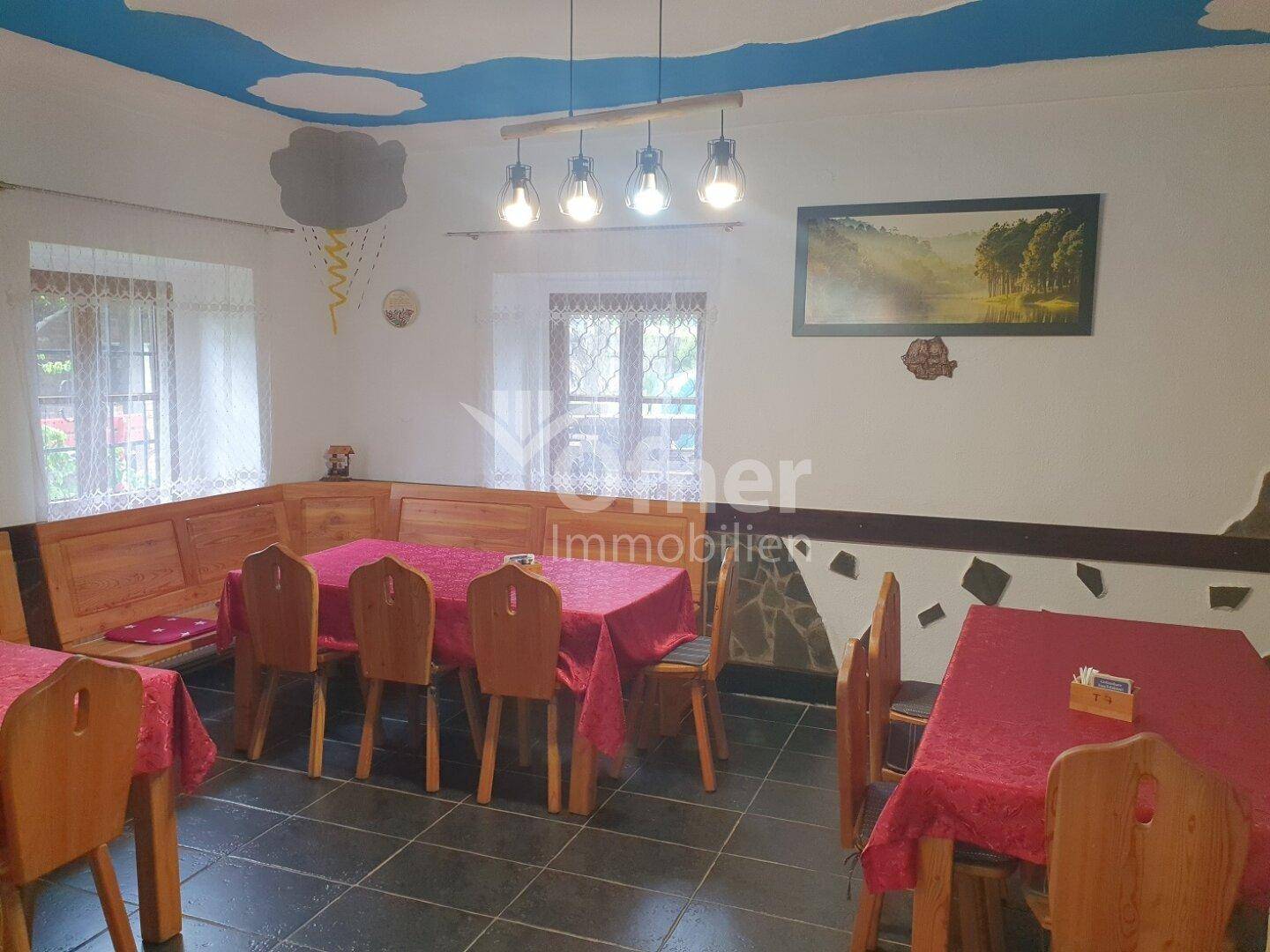 Einladender Essbereich mit Holzbänken, traditionellen Tischen und einer bemalten Decke.