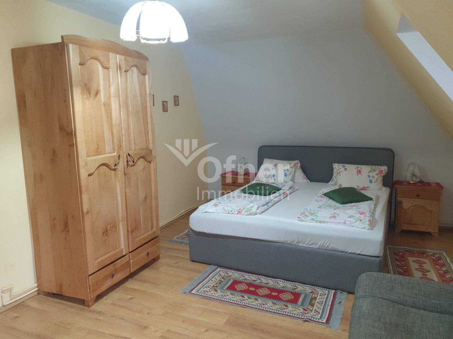Helles Schlafzimmer mit Holzboden, großem Kleiderschrank und schrägen Wänden im Dachgeschoss.