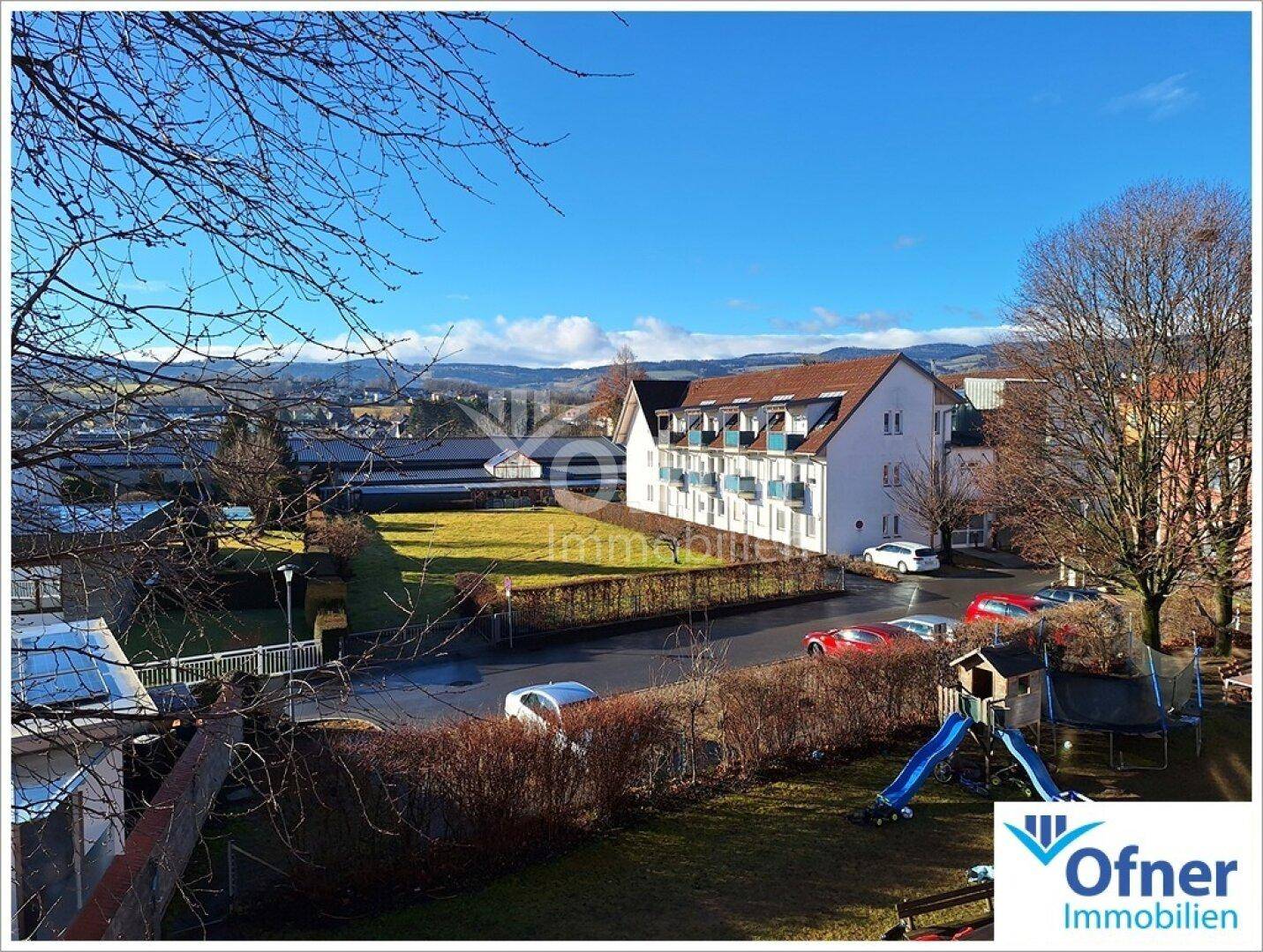 Weitläufiger Blick über die Nachbarschaft mit Wohnhäusern, Straße und grüner Landschaft.