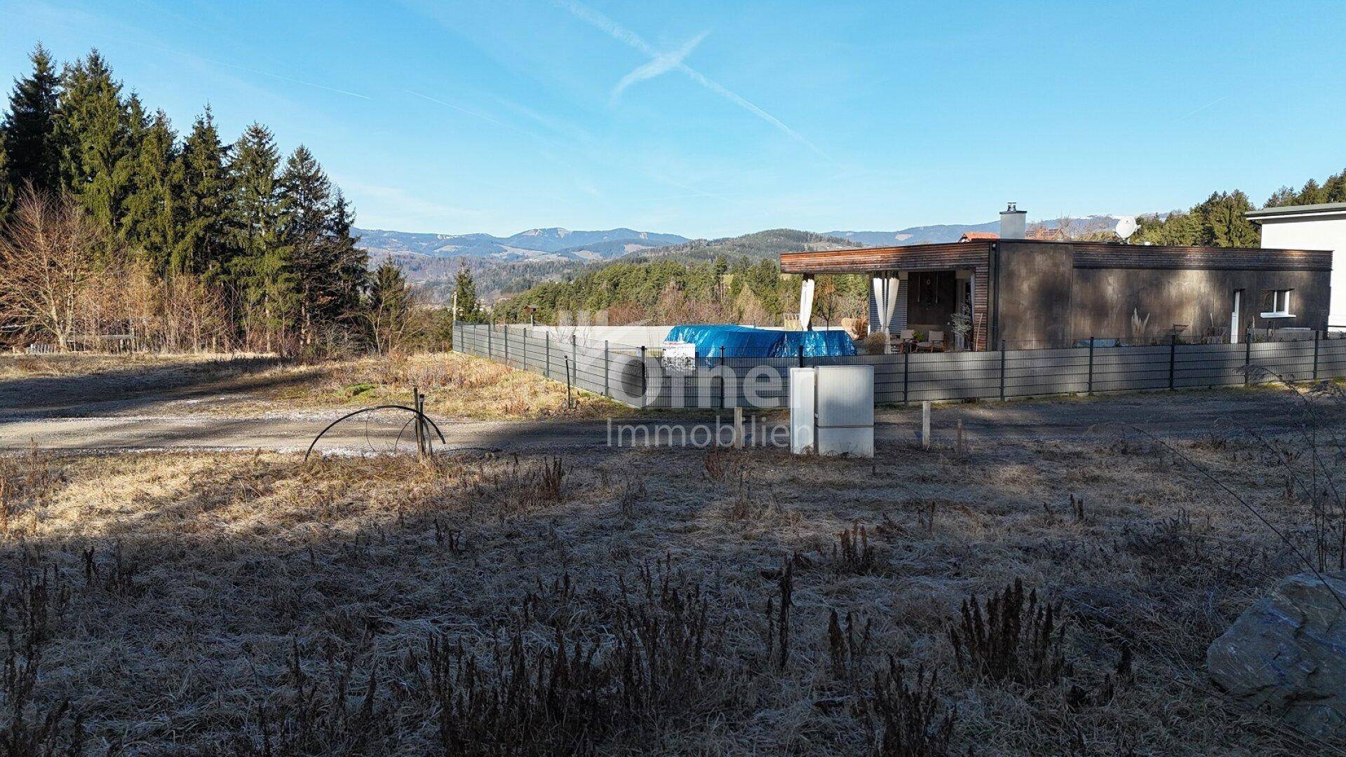 Großes Grundstück mit Blick auf die umliegende Natur und einen Poolbereich im Hintergrund.
