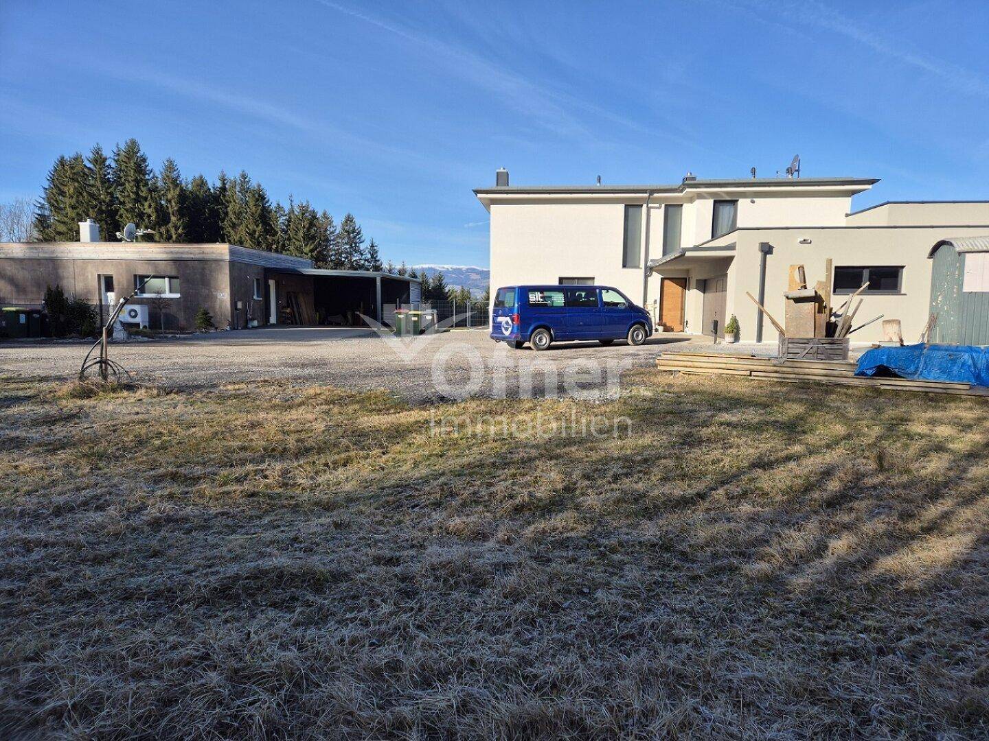 Modernes Wohnhaus mit Nebengebäude und großem Vorgarten, umgeben von ländlicher Landschaft.
