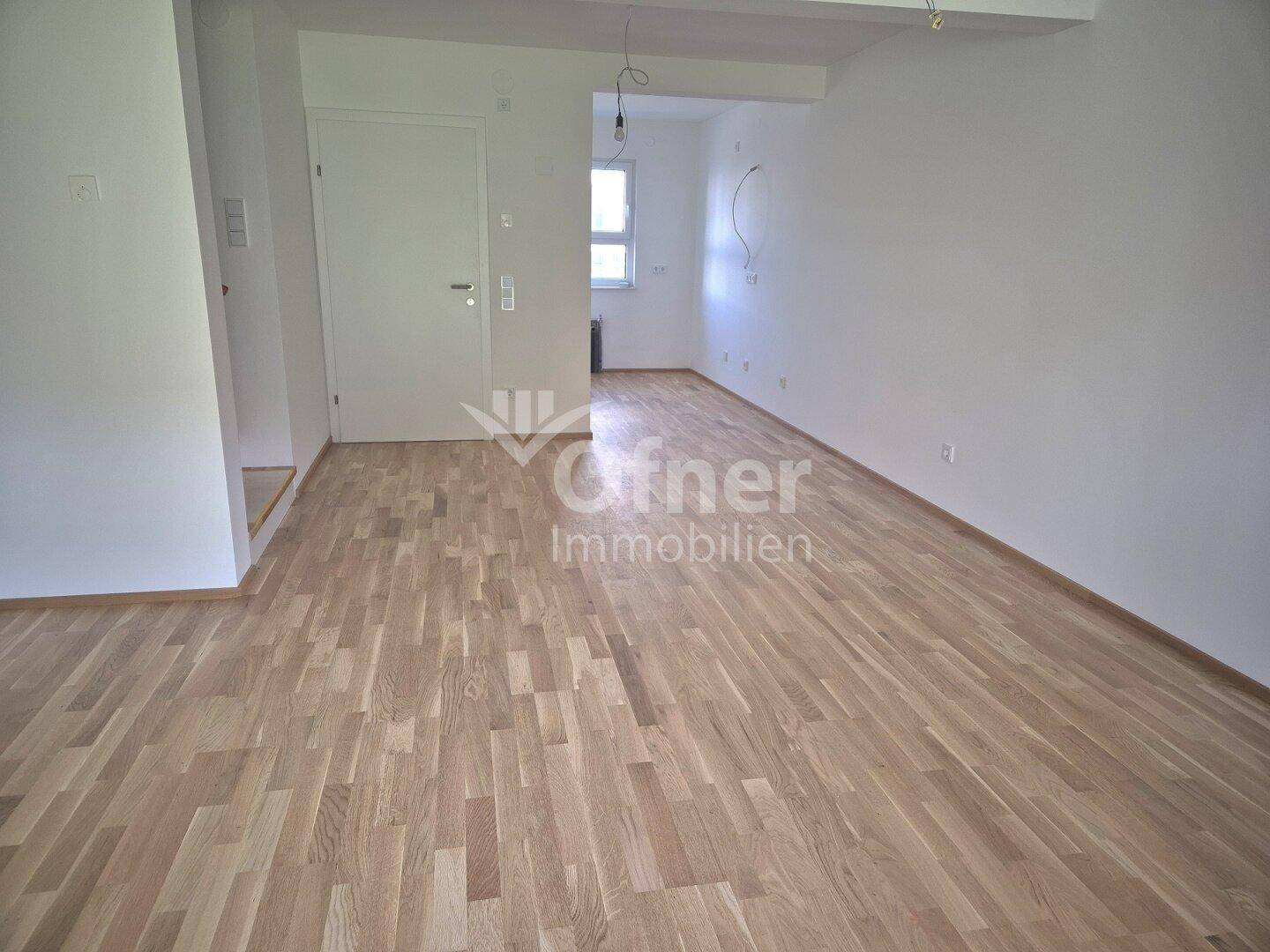 Heller, leerer Raum mit neuem Parkettboden und weiß gestrichenen Wänden, bereit zum Einzug.