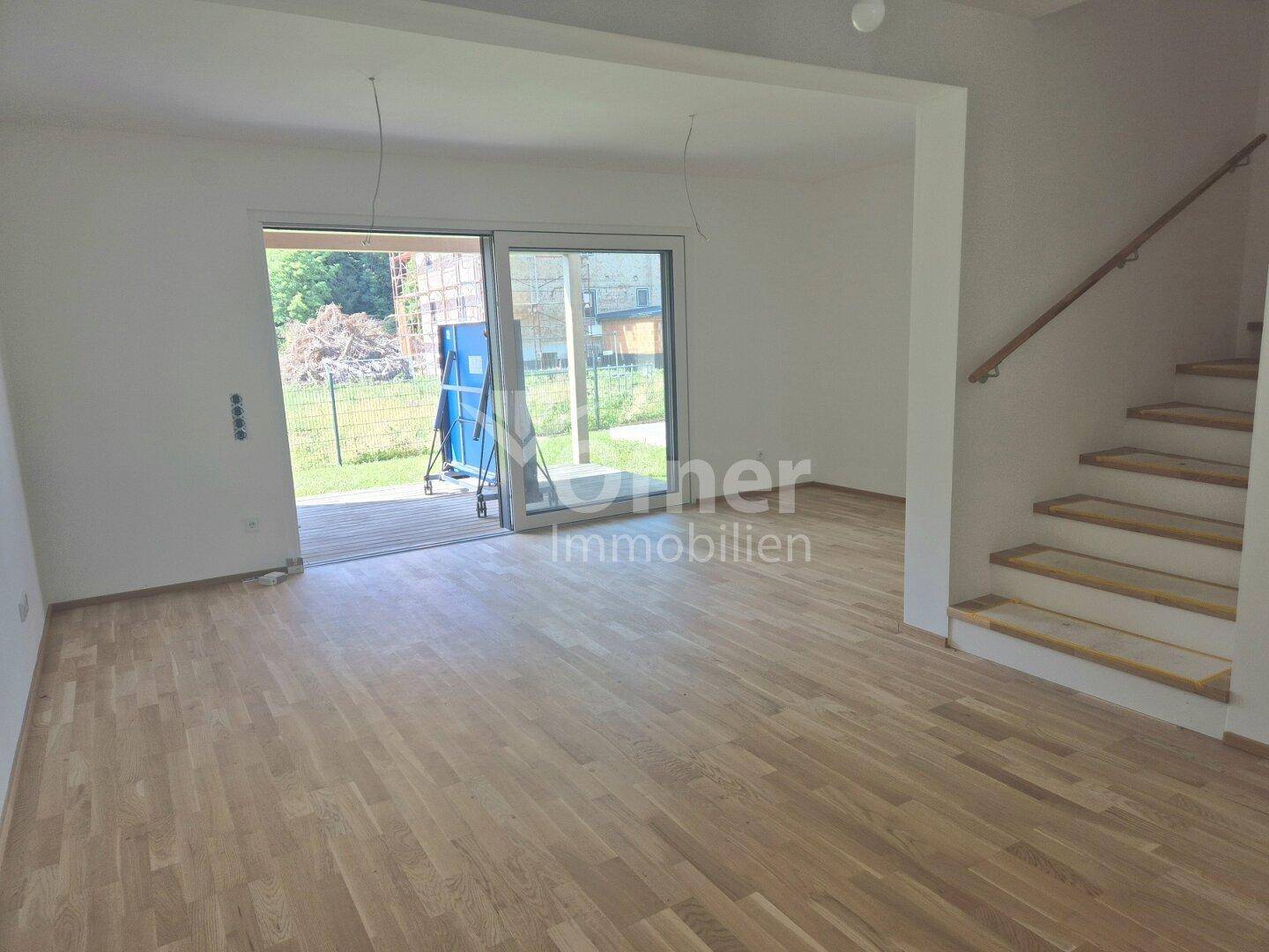 Geräumiger Wohnbereich mit Parkettboden und Zugang zu einer Außenterrasse, hell und offen.
