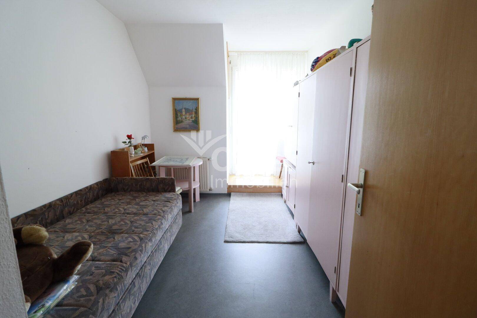Helles Zimmer mit Schlafsofa, Schrank und Zugang zu einem Balkon oder einer Loggia.