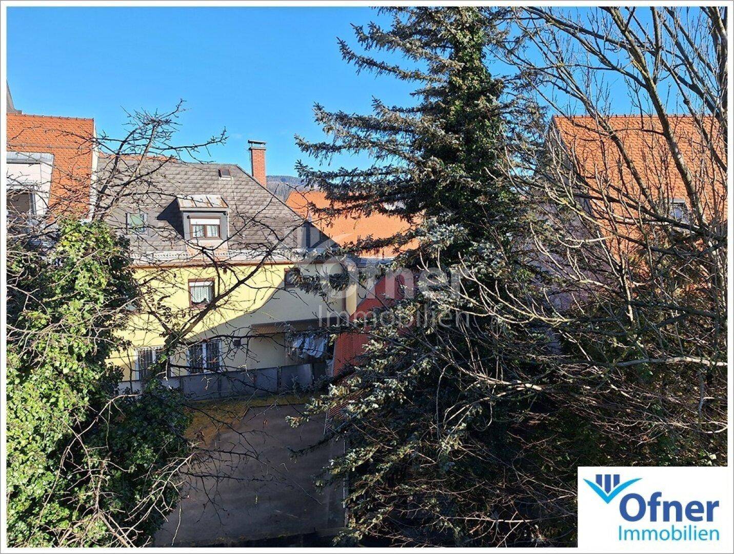 Blick auf die umliegende Wohnbebauung und Bäume unter einem klaren blauen Himmel.