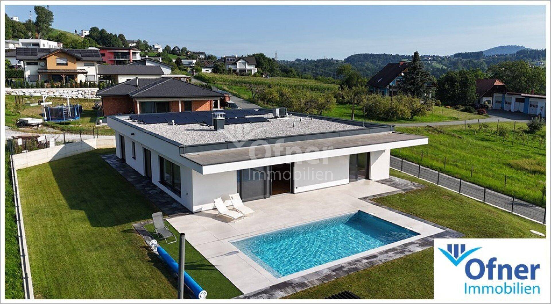 Luftaufnahme der modernen Villa mit Poolbereich, Liegestühlen und Blick auf die umliegende Landschaft.