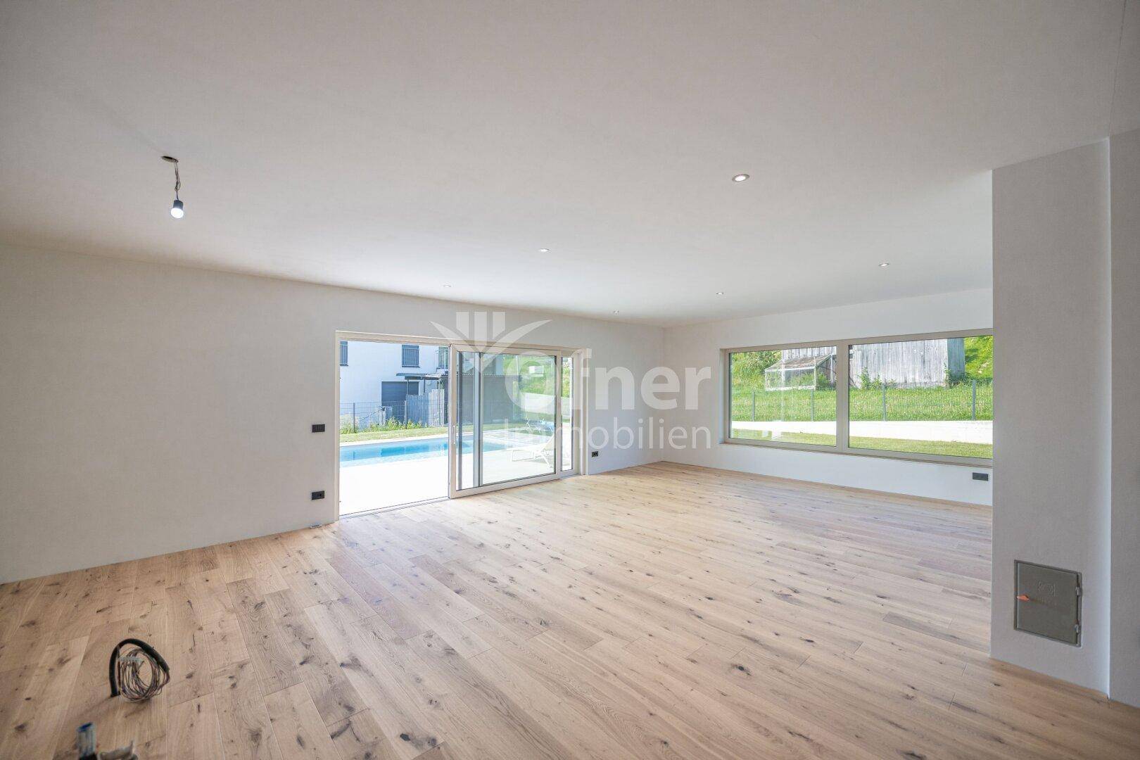 Heller Wohnraum mit Holzboden und weitem Blick auf den Pool und die umliegende Landschaft.