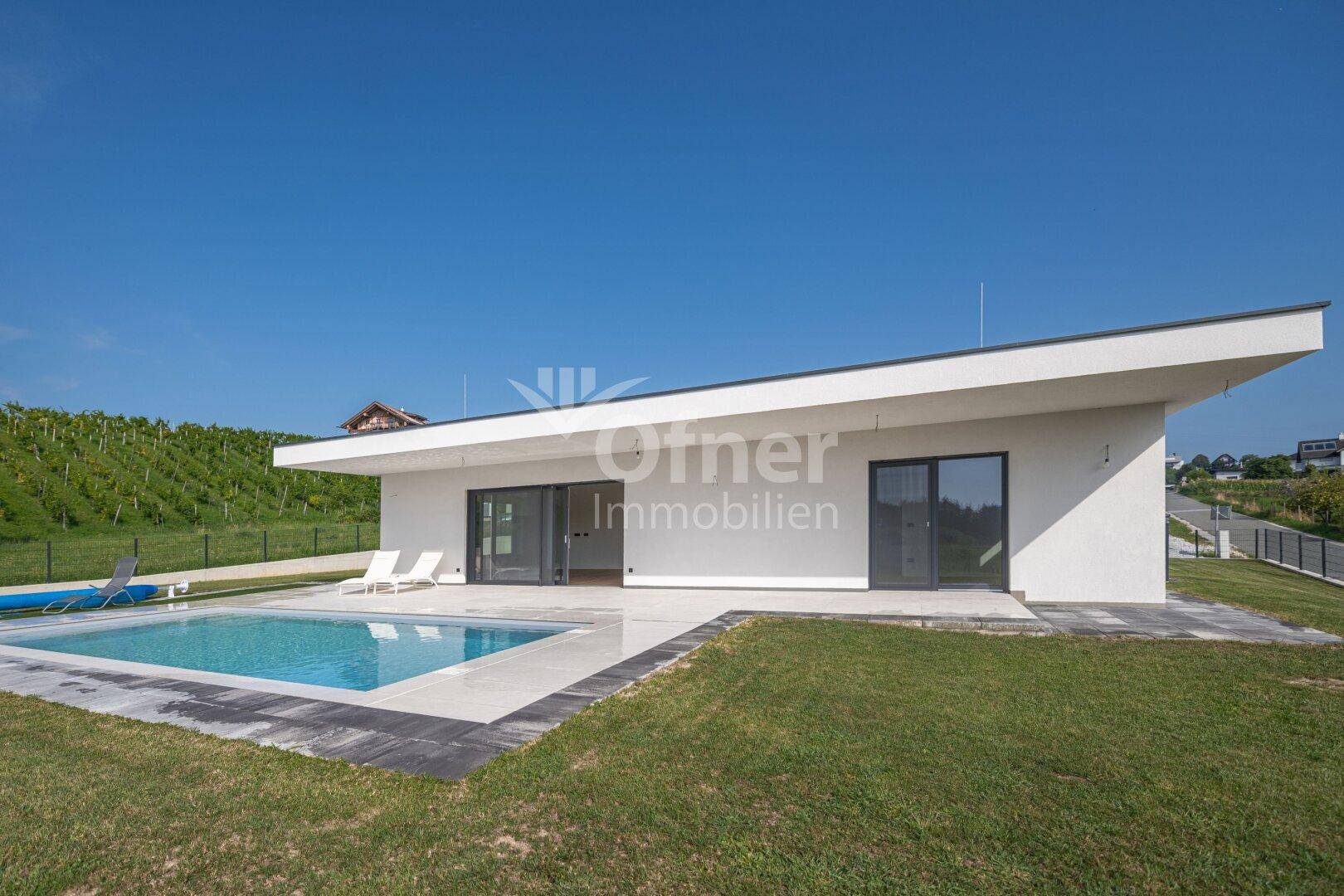 Moderne Villa mit Flachdach, Pool und weitläufigem Garten in ländlicher Umgebung.