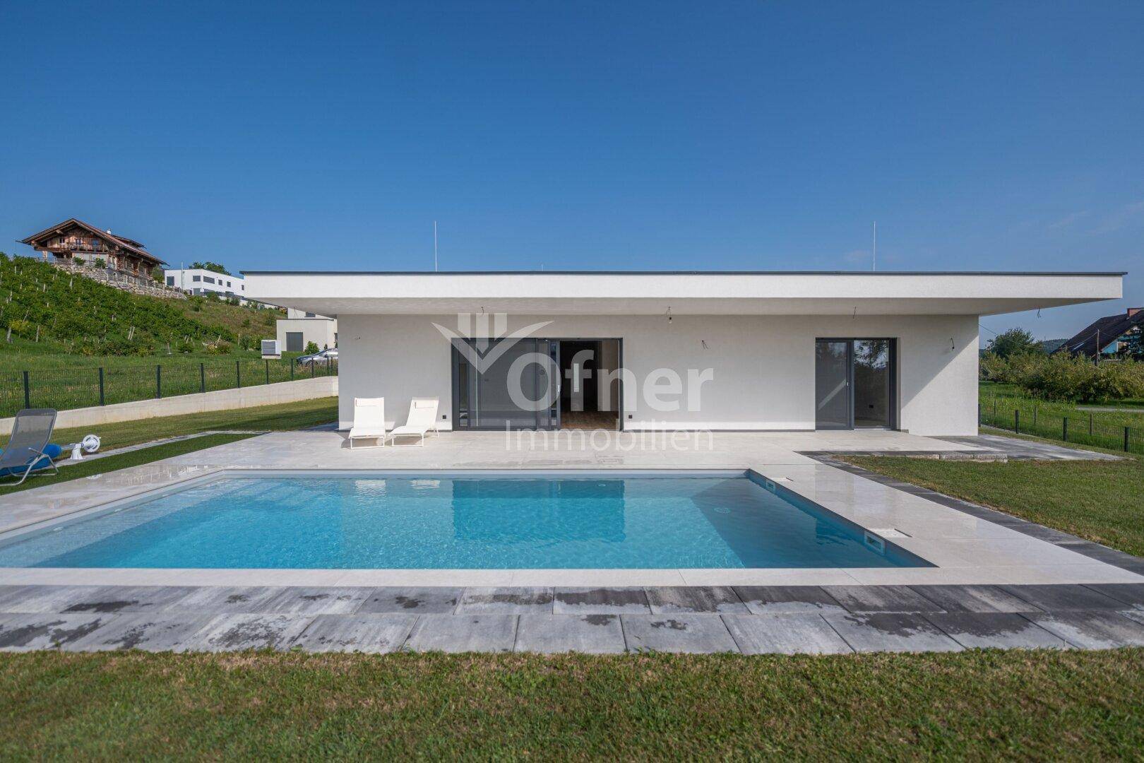 Elegantes Einfamilienhaus mit klaren Linien, großem Pool und gepflegtem Rasen.
