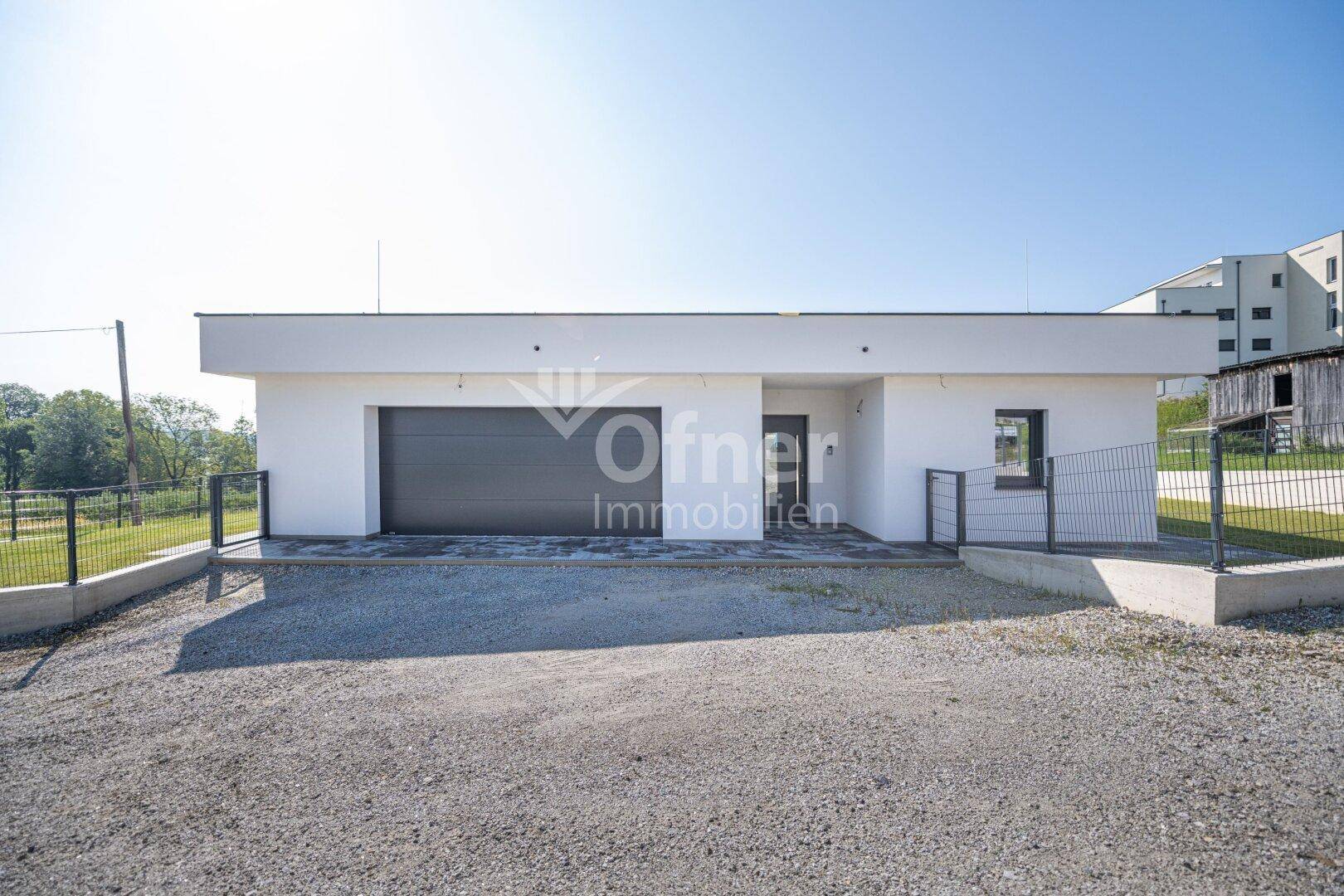 Frontansicht des modernen Hauses mit integrierter Garage und Schotterauffahrt.