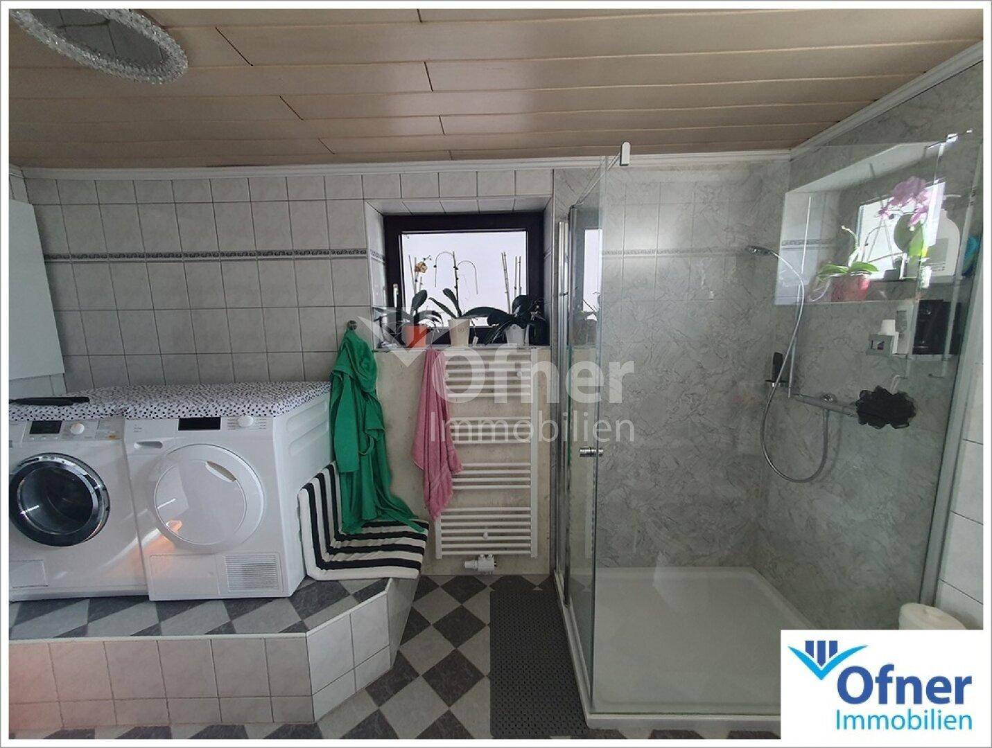 Modernes Badezimmer mit Duschkabine, Waschmaschine und Trockner.