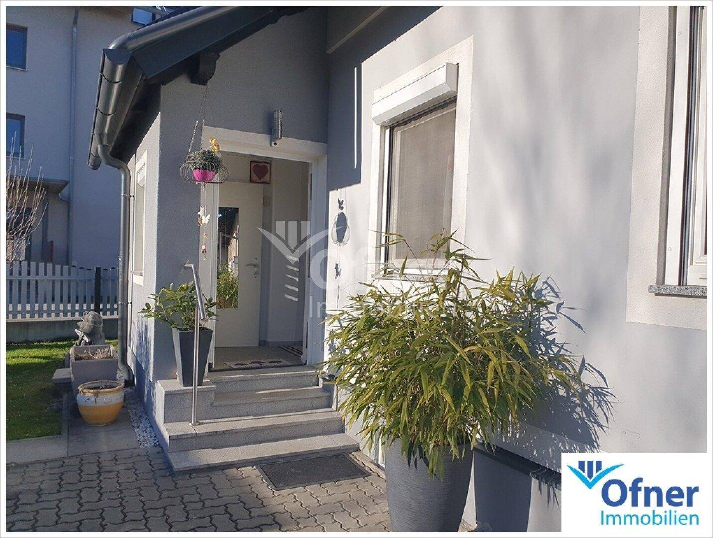 Eingangsbereich des Hauses mit Treppe und dekorativen Pflanzen.