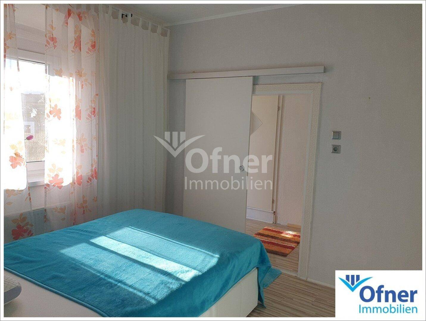 Helles Schlafzimmer mit großem Bett, Fenster und Schiebetür.