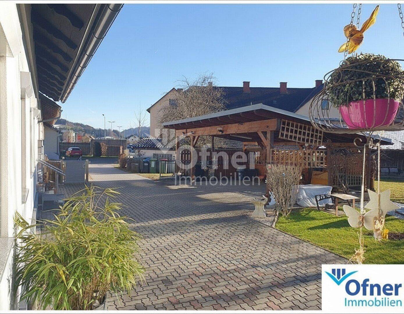 Gepflasterte Einfahrt mit Carport und Zugang zum Haus.