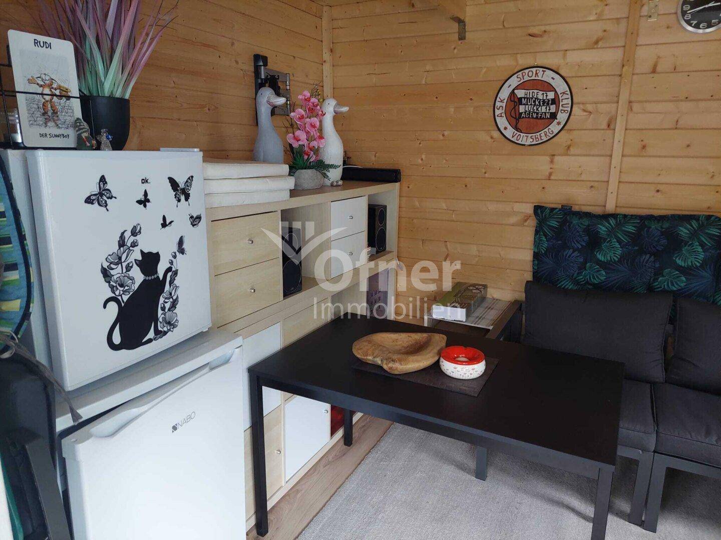 Gemütlicher Innenraum eines Gartenhauses mit Holzverkleidung und Sitzgelegenheiten.