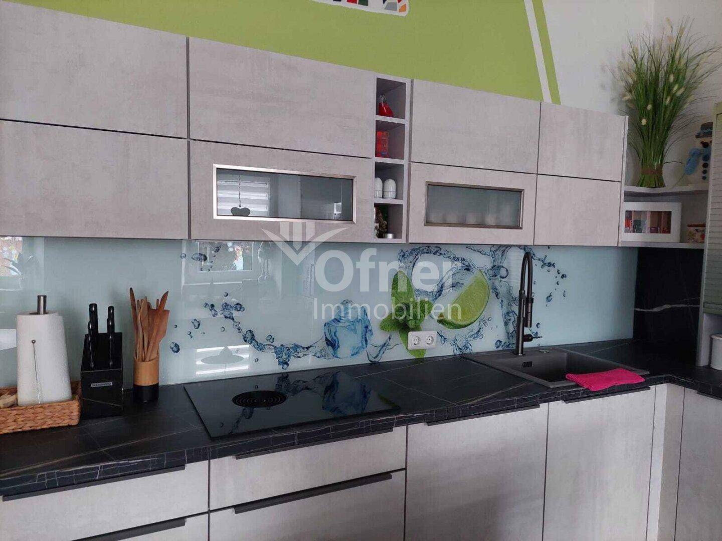 Detailansicht der modernen Küche mit Induktionskochfeld und kreativer Spritzschutzwand.